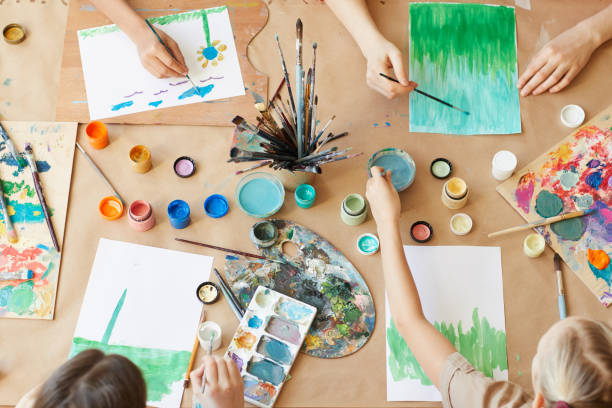 High angle view of group of children painting their pictures with watercolor paints during art lesson